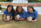 Mom and daughters smiling in front of hospital.