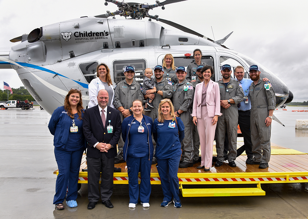 Group of people posing for photo beside helicopter