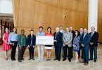 Couple holding large check with people standing around