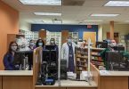 Six employees stand behind pharmacy counter