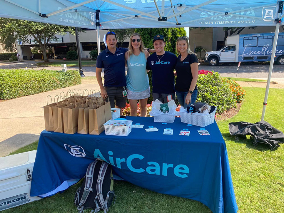 Four people stand in front of AirCare table