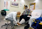 Man wrapping bandage around woman's leg