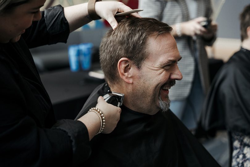 Man laughing while getting a haircut