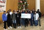 Group of people in front of a Christmas tree holding a big check