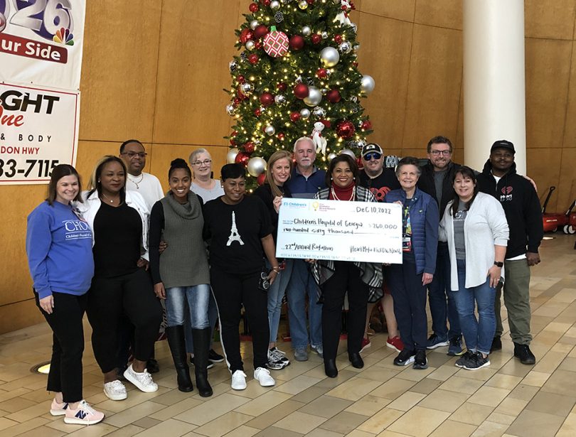 Group of people in front of a Christmas tree holding a big check