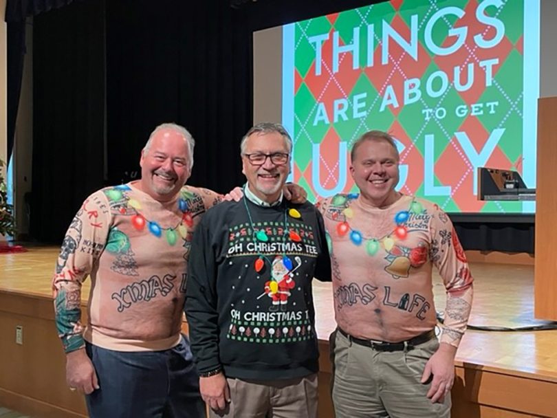 Three men posing in ugly Christmas sweaters