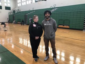 Man and woman pose for photo in high school gym