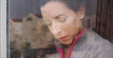 Woman crying behind rainy window