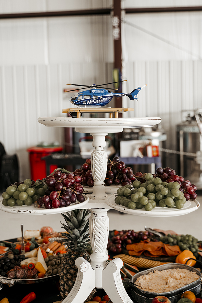 A miniature helicopter with AirCare logo sits on top of a display stand full of fruit.