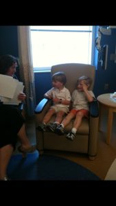 Two boys in a chair talking to an adult
