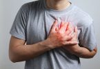 Man in gray shirt holding chest in heart attack