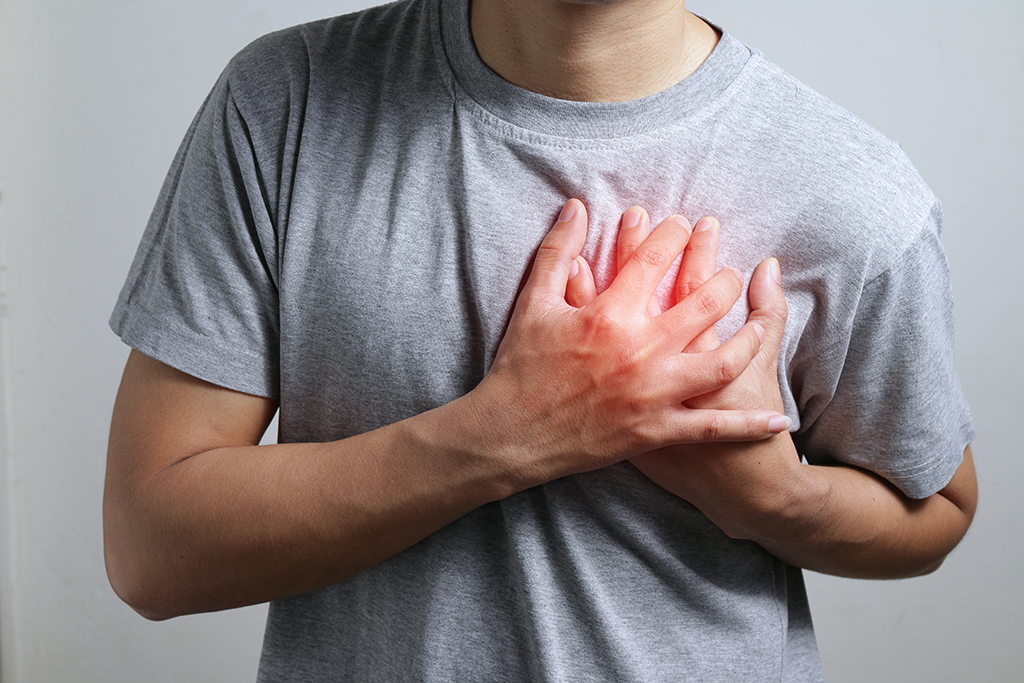 Man in gray shirt holding chest in heart attack