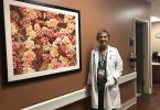 Woman standing beside a poster of flowers