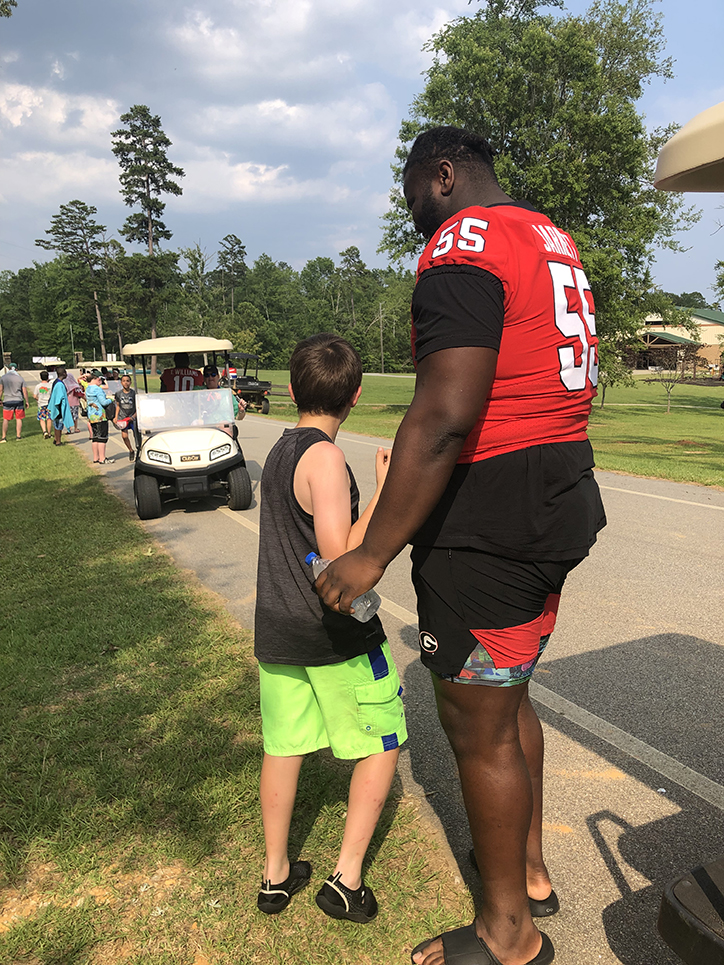 Football player talks to camper