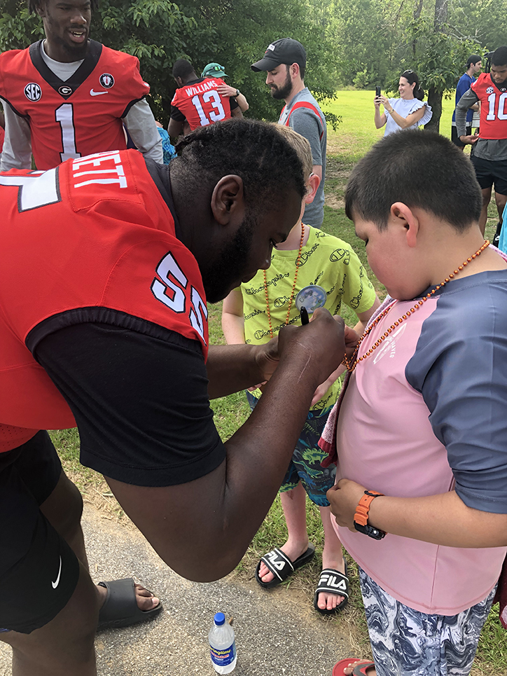 Football player signing autograph for young boy