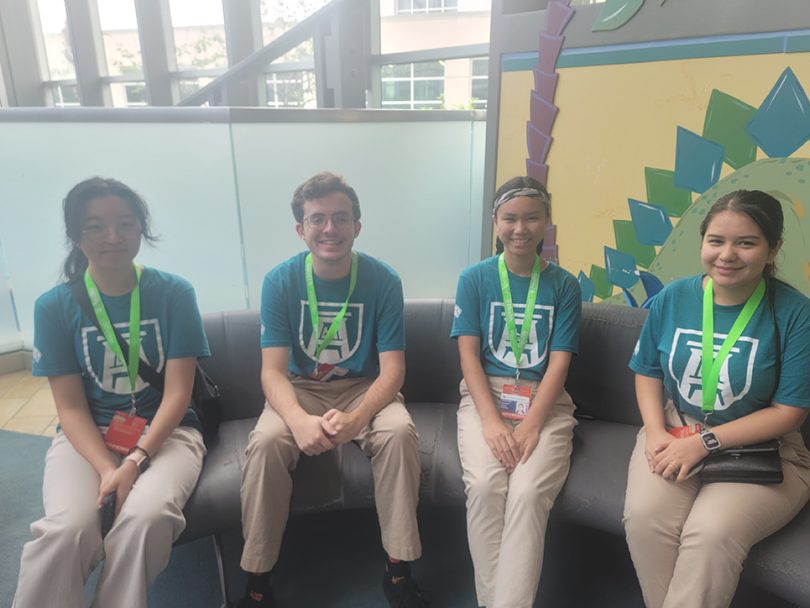 Four students in T-shirts sit on couch in Children's lobby