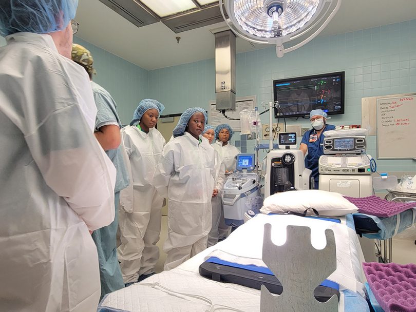 Students in bunny suits standing around operating room table