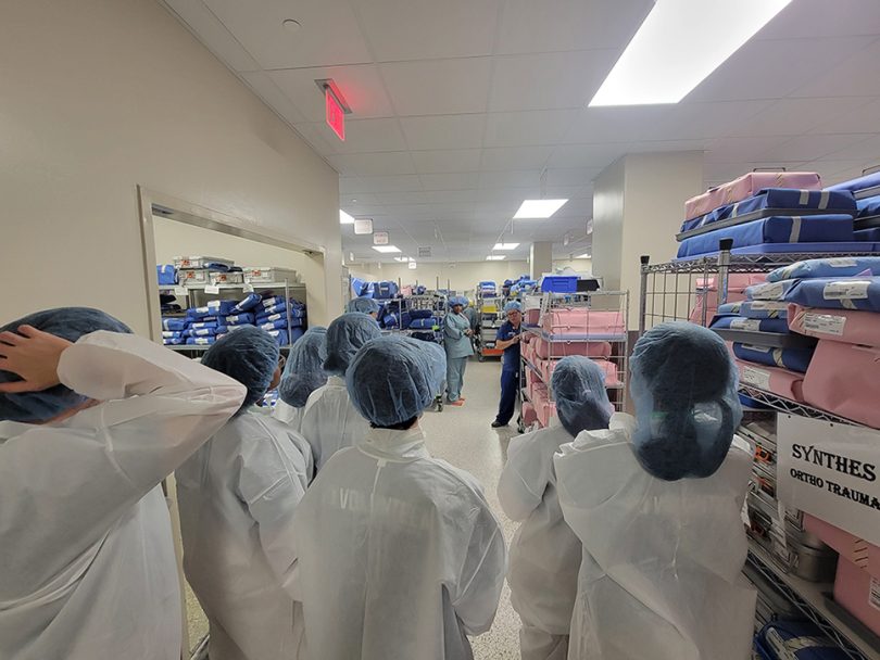 Students in bunny suits in the operating room supply room