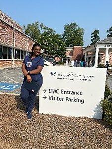 Woman posing for photo beside a sign