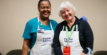 Two patient and family providers pose while serving food at the Wellstar MCG Health all-star breakfast