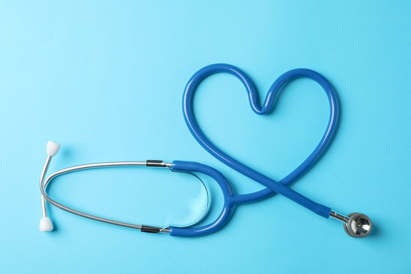 Stethoscope in shape of heart on blue background