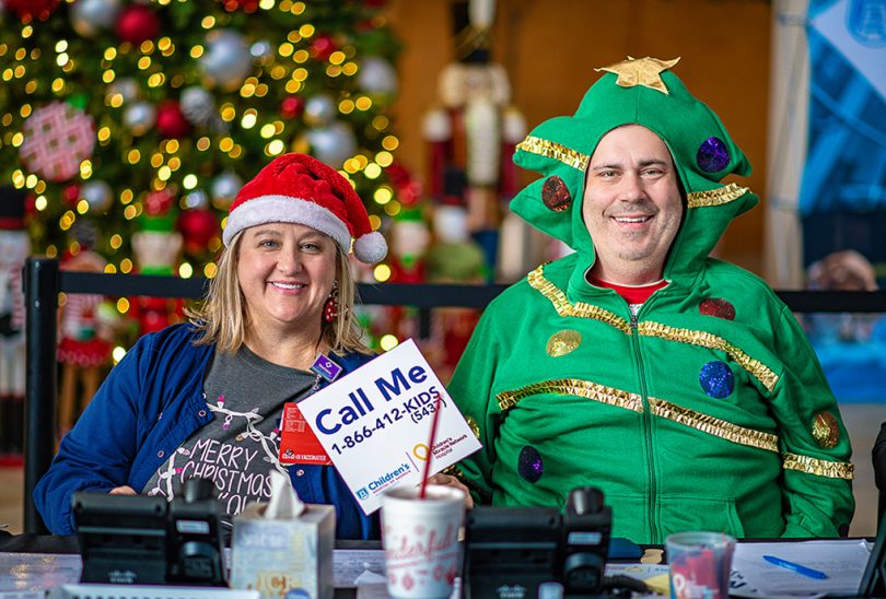 Woman in Santa hat and man in Christmas tree costume