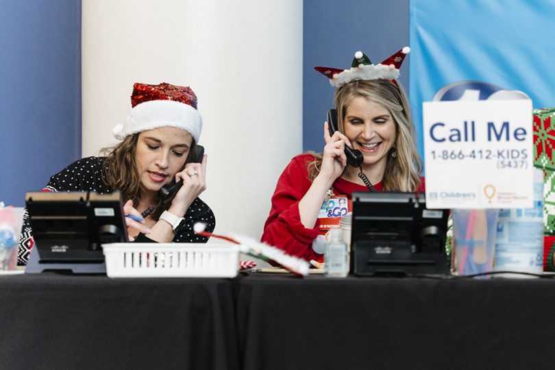 Two women in santa hats on telephones