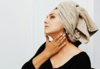 Woman with towel on head checking neck