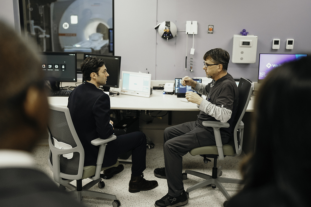 Two men talking in front of a computer and MRI machine