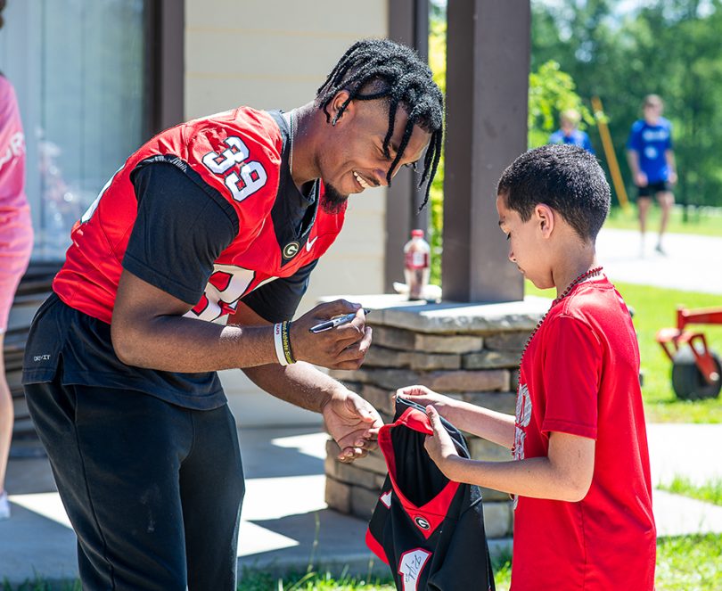Man in a football jersey signs a shirt for a young teen