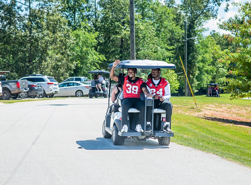 Football players ride on the back of a golf cart