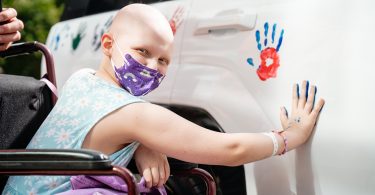Cancer patient in mask makes hand print on car