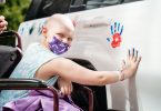 A patient puts her handprint on a white car